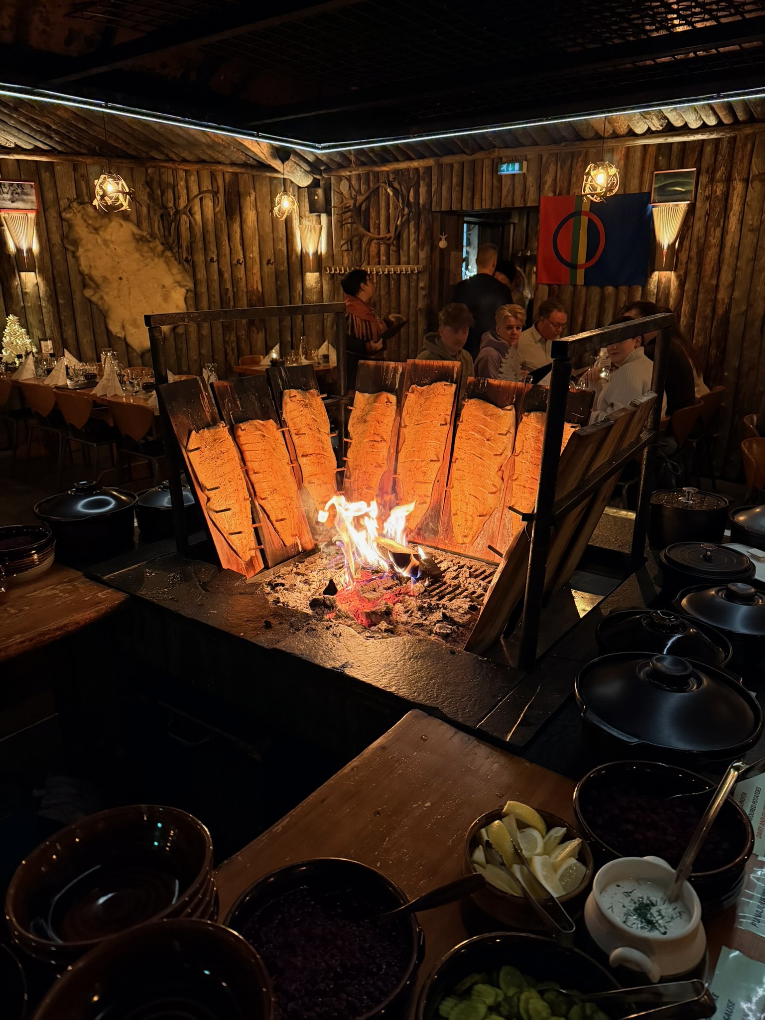 Salmon fillets on wooden boards being grilled over the open fire — the smell was incredible